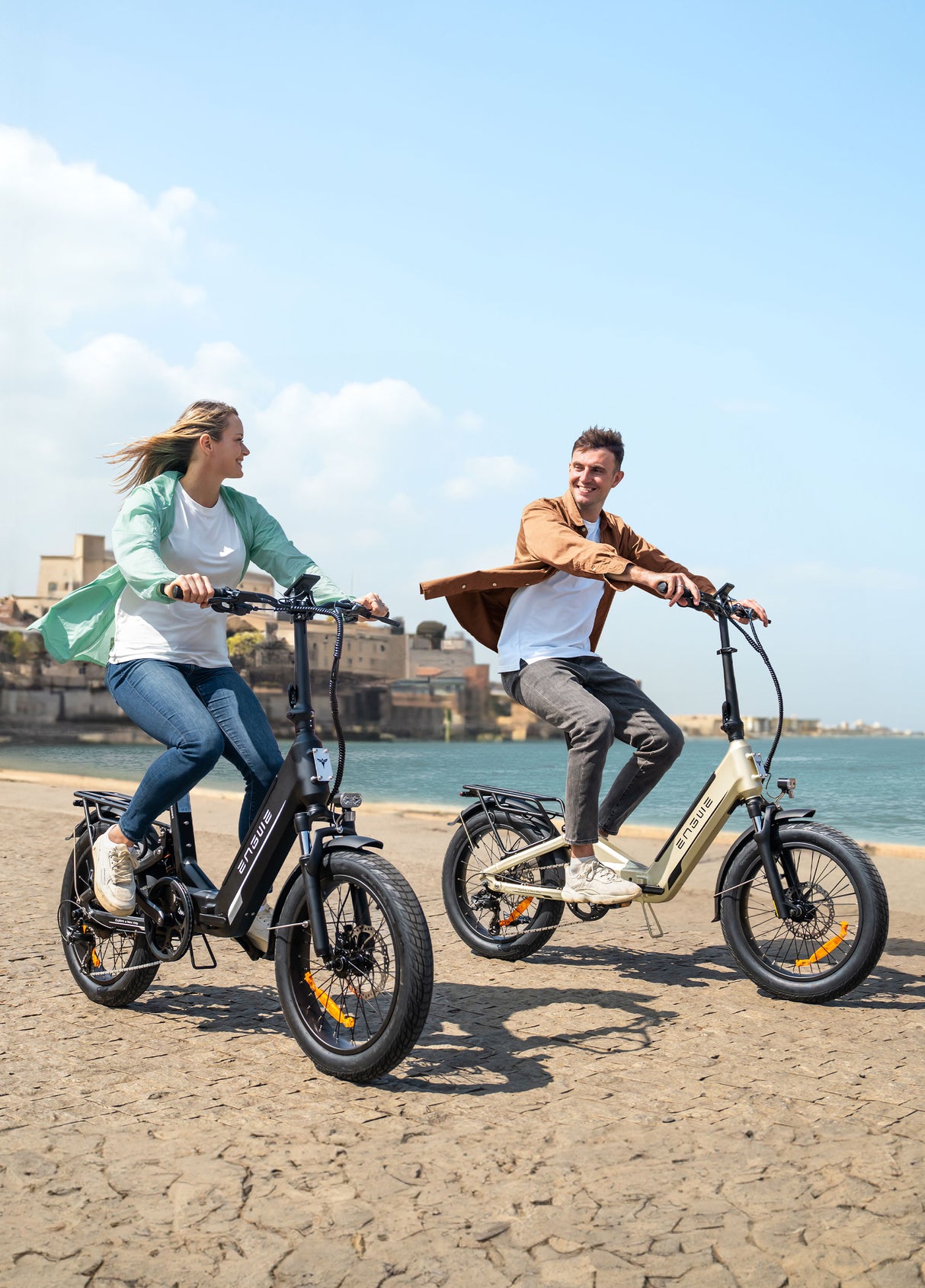 a man and a woman riding engwe l20 3.0 boost folding ebikes on the beach