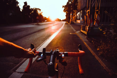 on the highway at sunset, a person holds the front of an adult electric bike with one hand