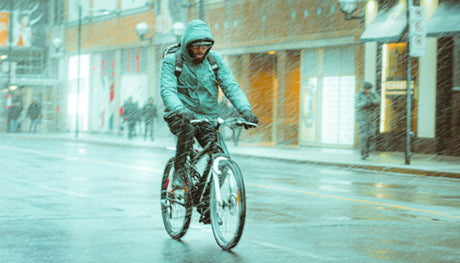 man in jacket riding bicycle in the rain